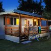 Una casa mobile illuminata con veranda, tavolo, sedie e biciclette.